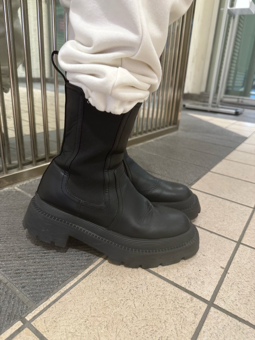 ホワイト系のスウェットパンツ、ホワイト系のスウェット、ブラック系のブーツを着用したレディースの秋コーディネートの7枚目の写真