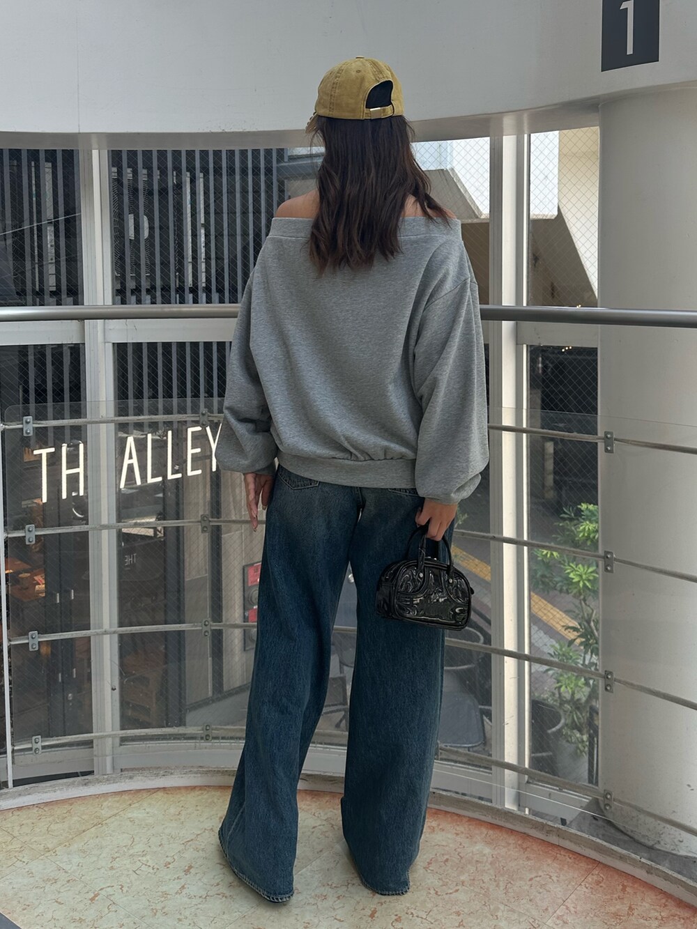 ブルー系のデニムパンツ、グレー系のパーカー、ブラック系のハンドバッグを着用したレディースの秋コーディネートの4枚目の写真