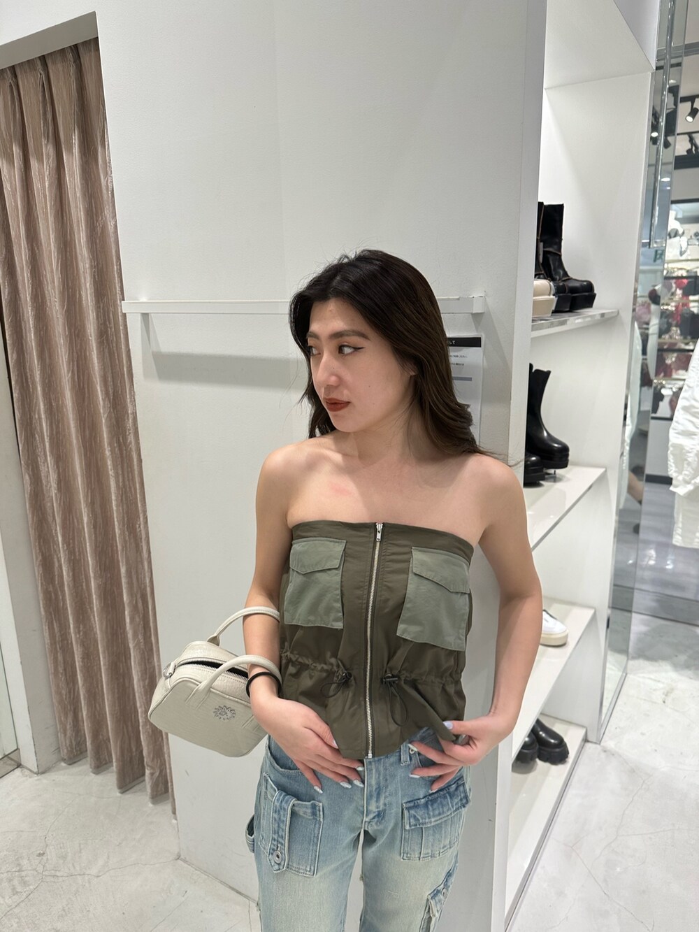 グリーン系のキャミソール、ブルー系のデニムパンツ、ホワイト系のショルダーバッグを着用したレディースの冬コーディネートの5枚目の写真