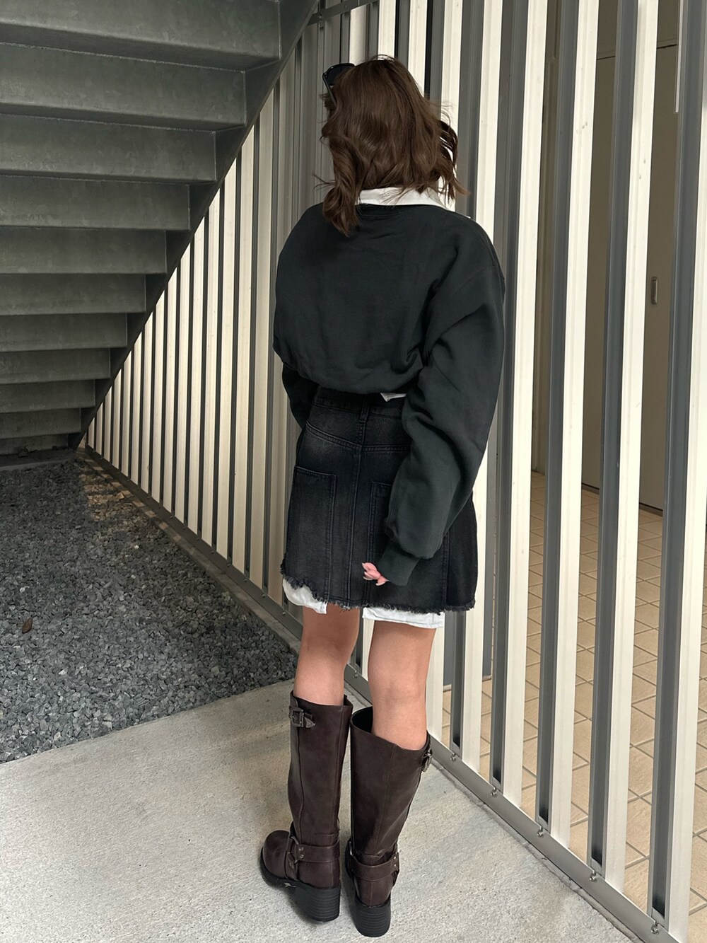 ブラック系のデニムスカート、ブラウン系のブーツ、ブラック系のスウェットを着用したレディースの冬コーディネートの3枚目の写真