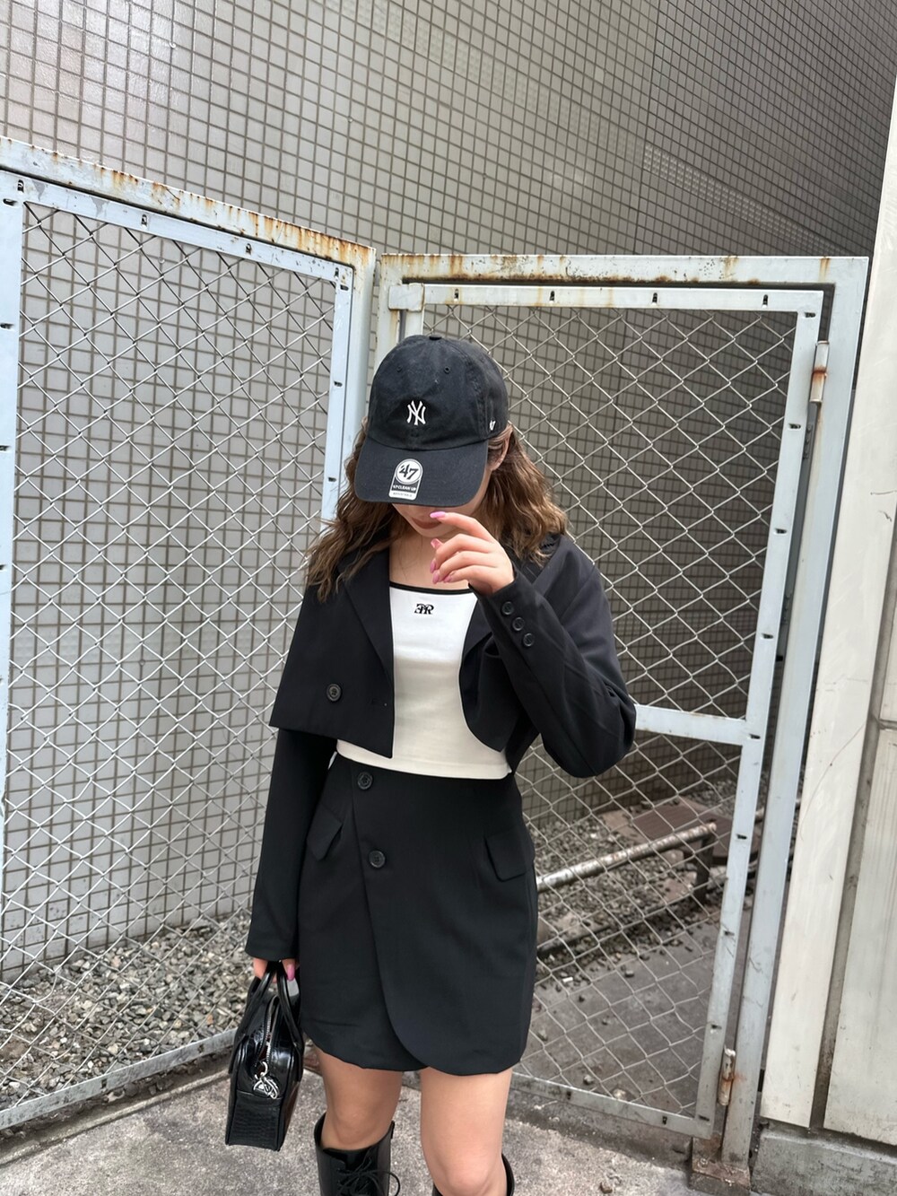 ホワイト系のTシャツ/カットソー、ブラック系のテーラードジャケット、ブラック系のスカートを着用したレディースの春コーディネートの4枚目の写真