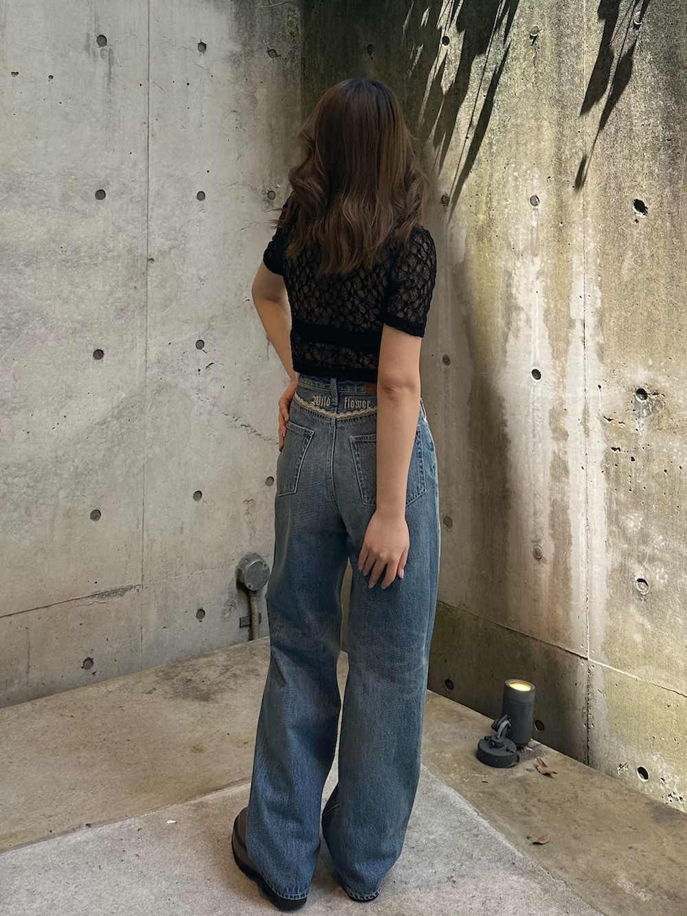 ブルー系のデニムパンツ、ブラウン系のブーツ、ブラック系のTシャツ/カットソーを着用したレディースの春コーディネートの4枚目の写真