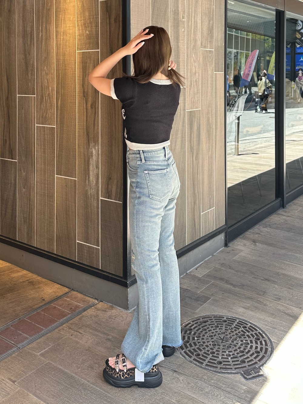 ブラック系のニット/セーター、ブルー系のデニムパンツ、その他のサンダルを着用したレディースの春コーディネートの2枚目の写真