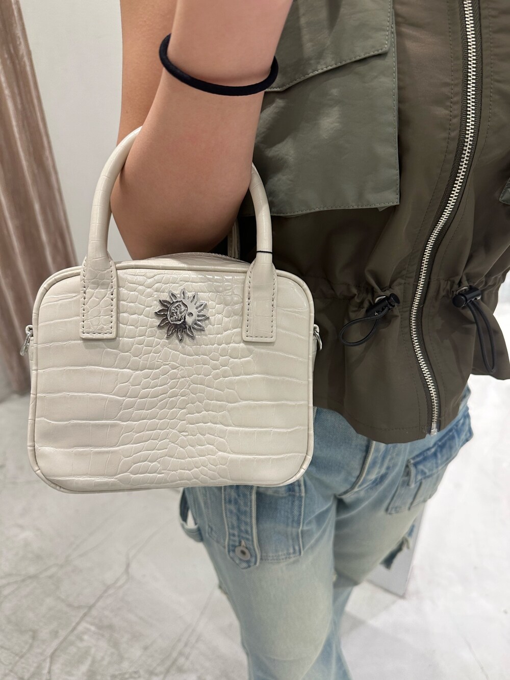 グリーン系のキャミソール、ブルー系のデニムパンツ、ホワイト系のショルダーバッグを着用したレディースの冬コーディネートの7枚目の写真