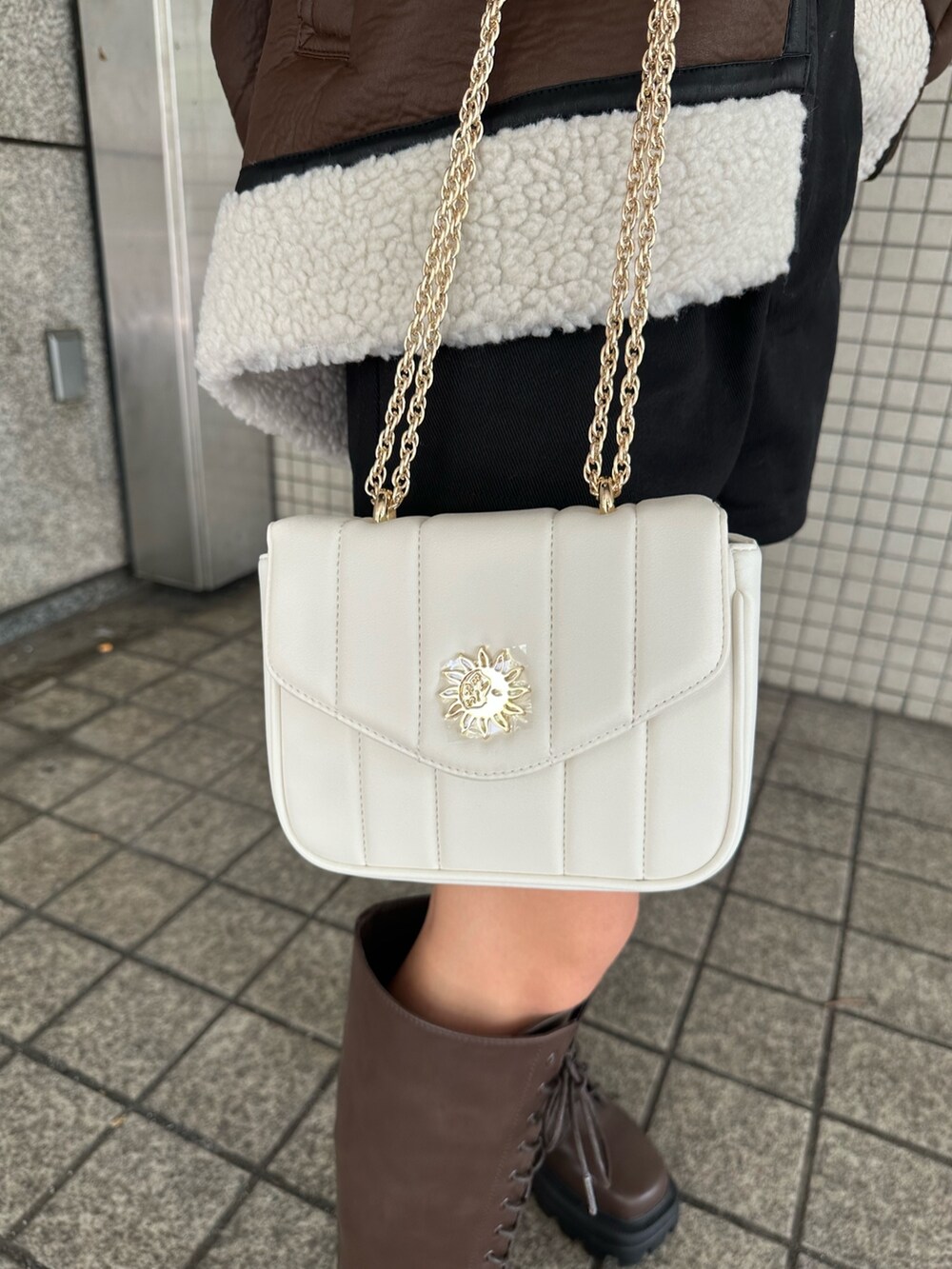 ブラック系のその他パンツ、ホワイト系のショルダーバッグ、ブラウン系のブーツを着用したレディースの夏コーディネートの6枚目の写真