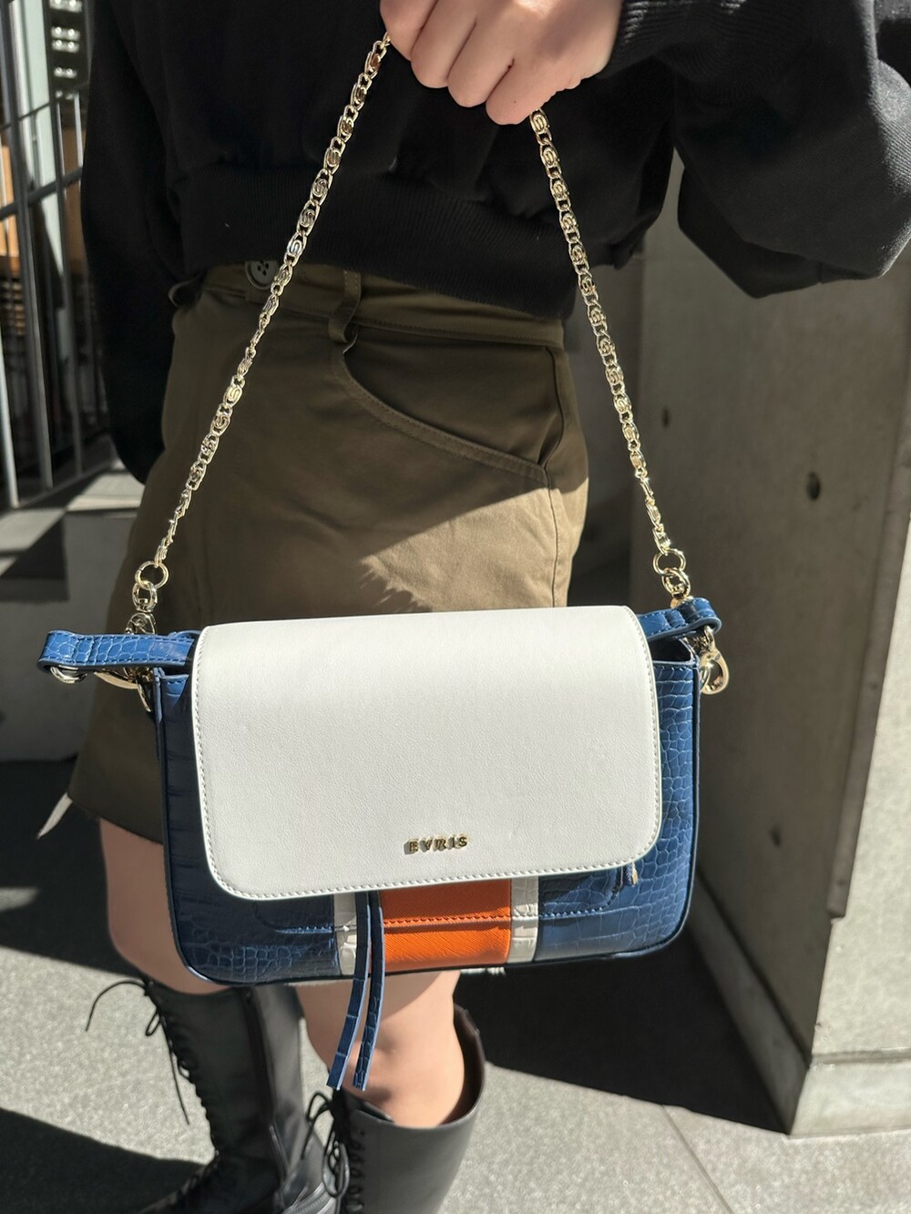 ブラック系のスウェット、ブラック系のブーツ、ブルー系のショルダーバッグを着用したレディースの冬コーディネートの6枚目の写真