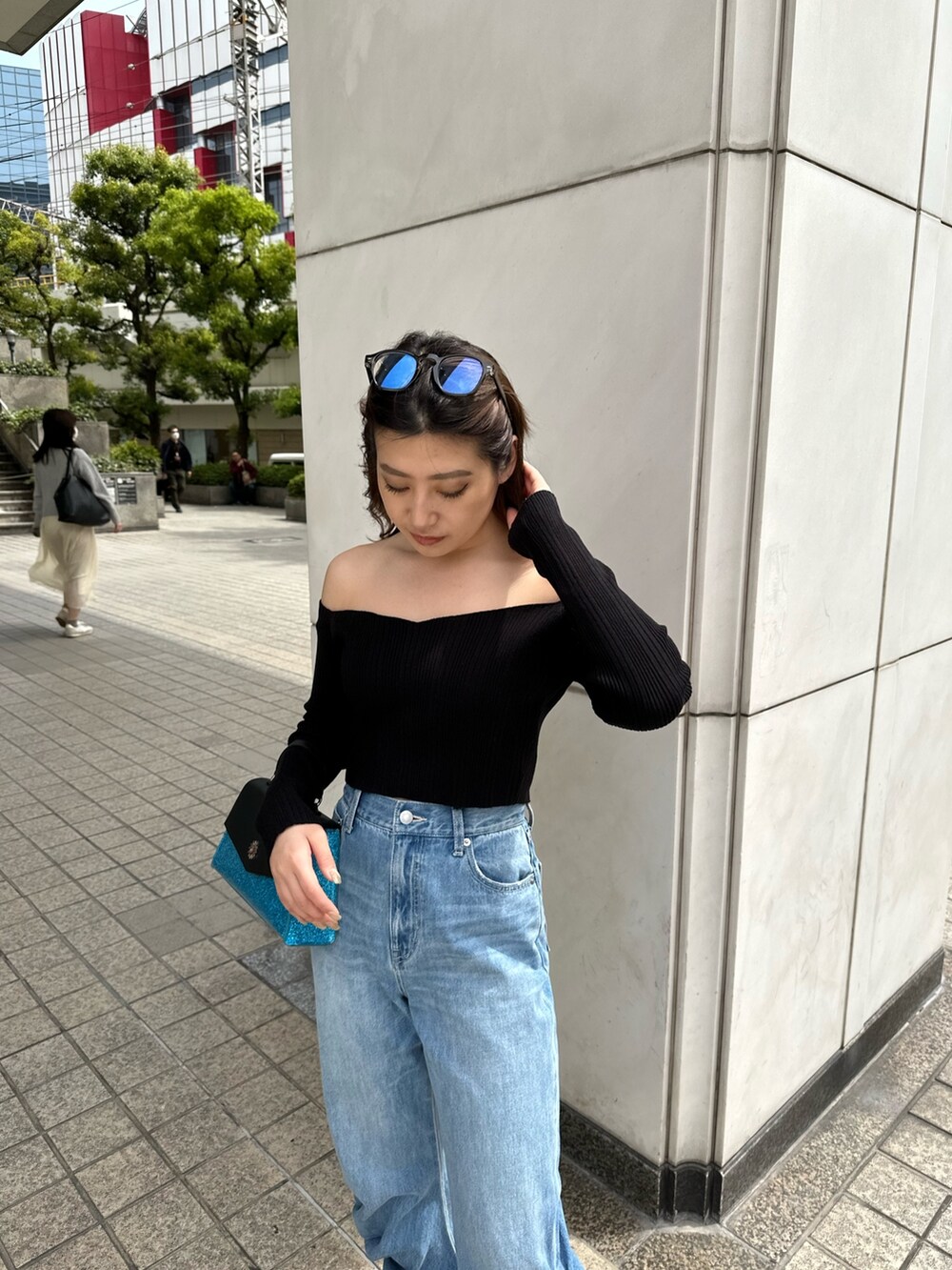 ブルー系のデニムパンツ、ブルー系のショルダーバッグ、ブラック系のニット/セーターを着用したレディースの春コーディネートの4枚目の写真