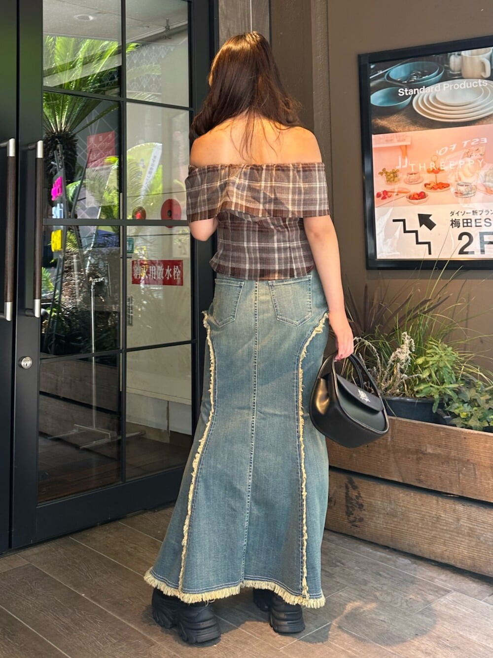 ブラック系のハンドバッグ、ブラック系のサンダル、ブルー系のデニムスカートを着用したレディースの夏コーディネートの3枚目の写真