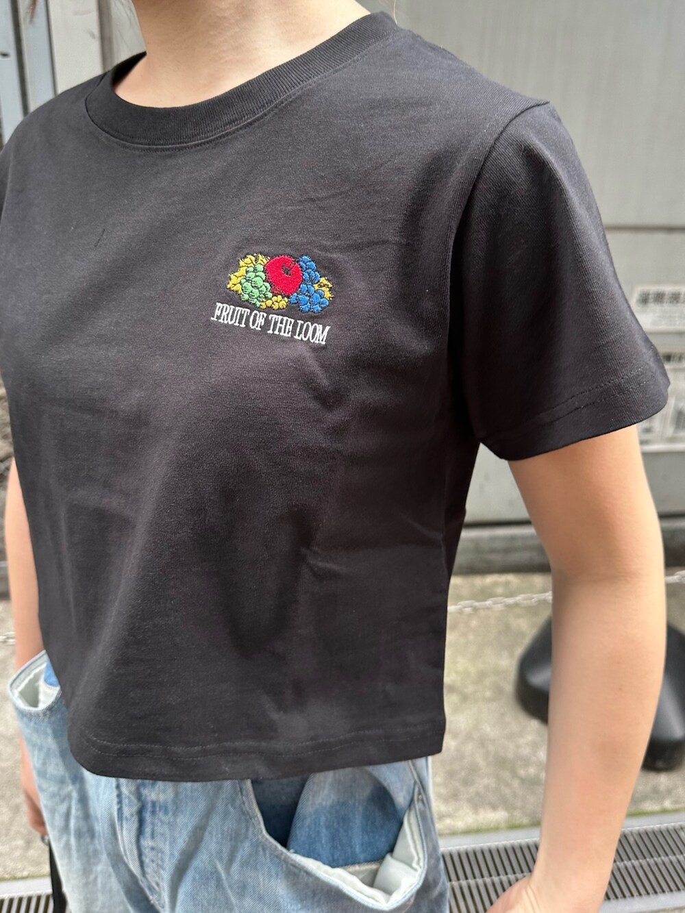 ブラック系のTシャツ/カットソー、ブラック系のスニーカー、ブルー系のデニムパンツを着用したレディースの春コーディネートの5枚目の写真