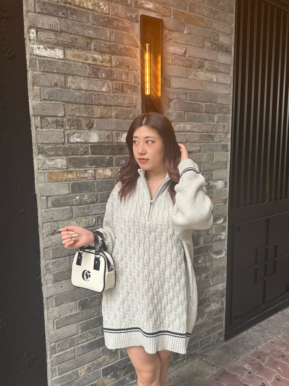 グレー系のニット/セーター、ホワイト系のショルダーバッグを着用したレディースの夏コーディネートの5枚目の写真