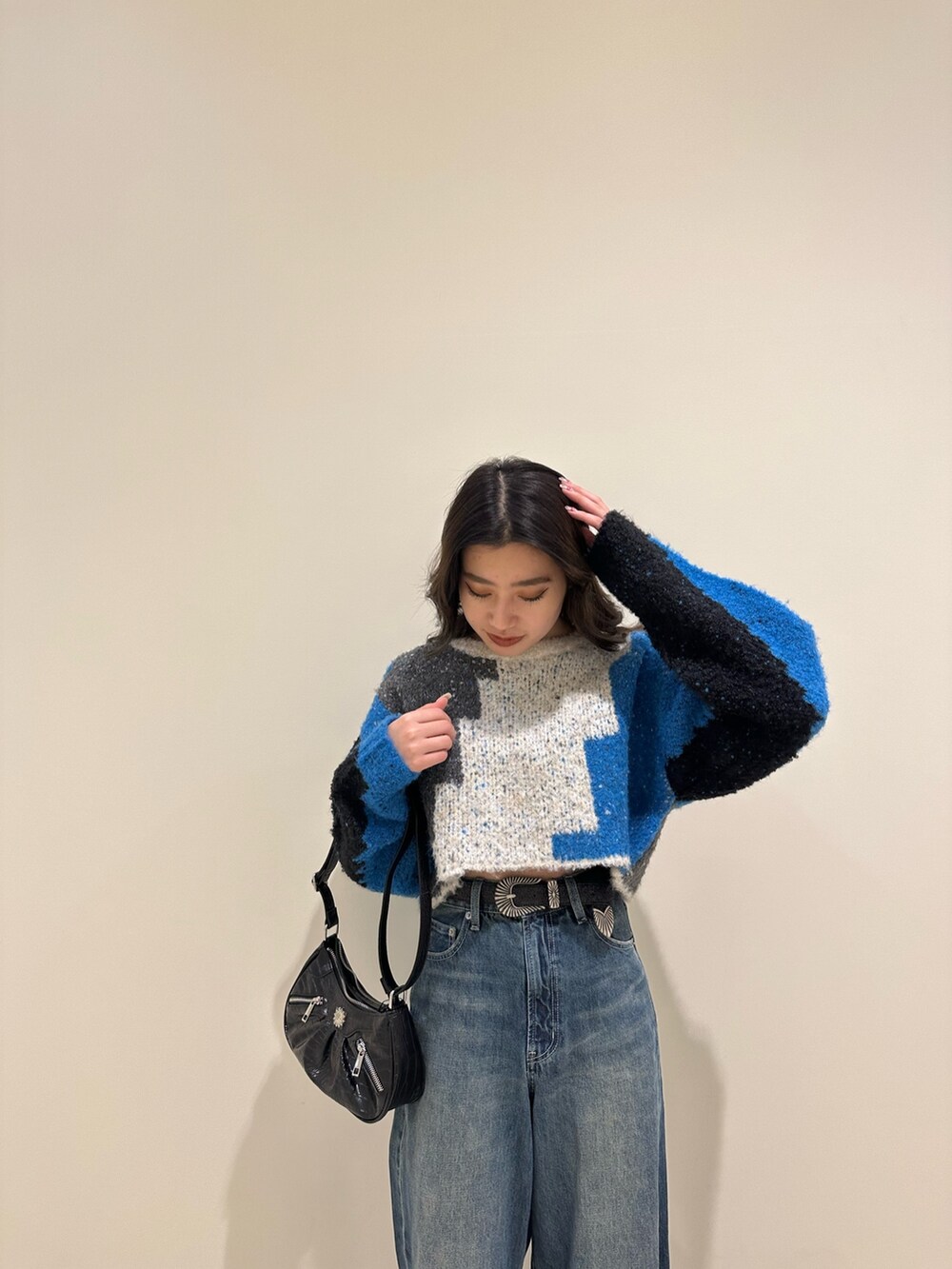 ブルー系のデニムパンツ、ブラック系のショルダーバッグ、ブラック系のブーツを着用したレディースの冬コーディネートの5枚目の写真