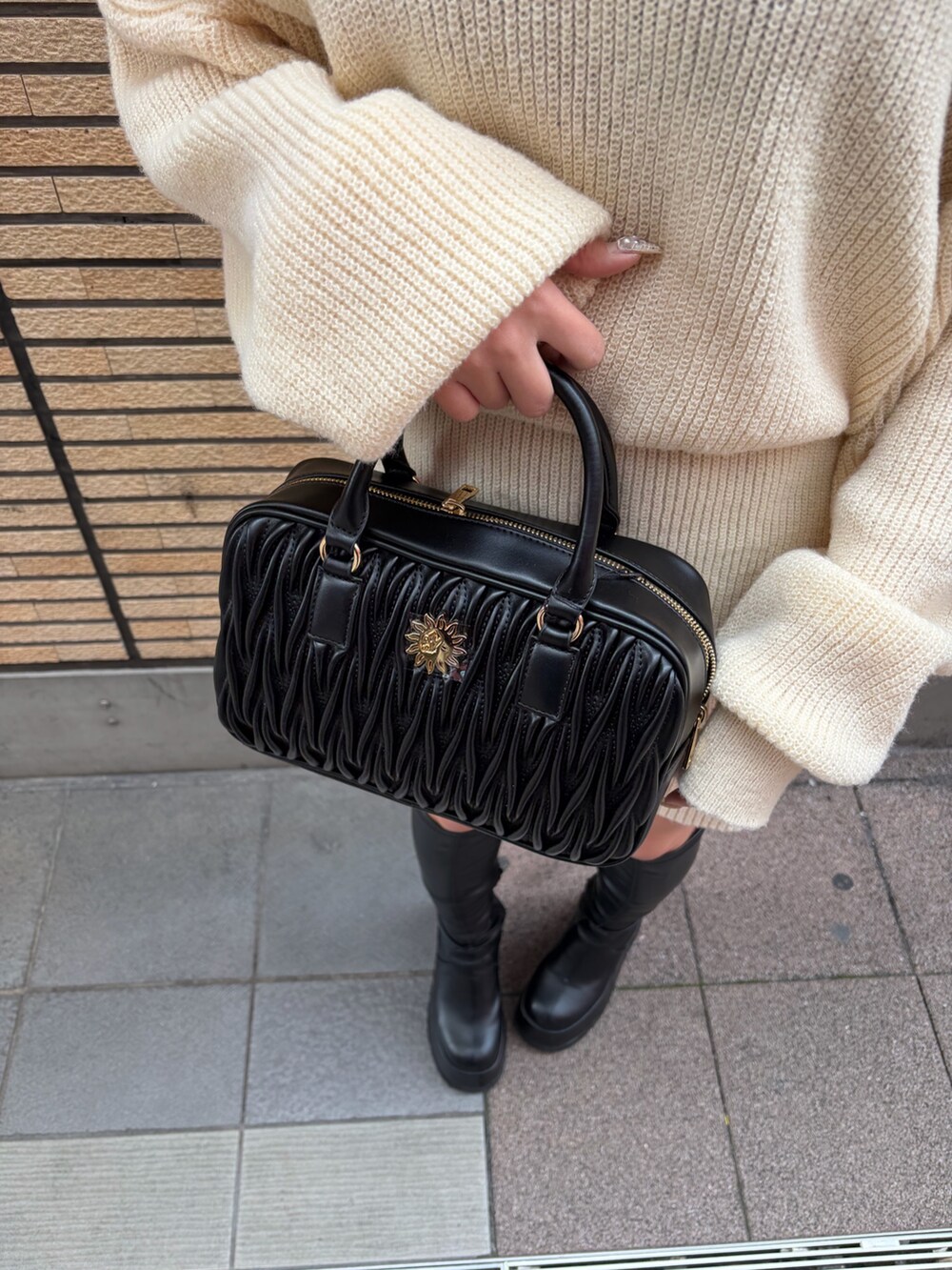 ブラック系のブーツ、ホワイト系のワンピース、ブラック系のハンドバッグを着用したレディースの冬コーディネートの6枚目の写真