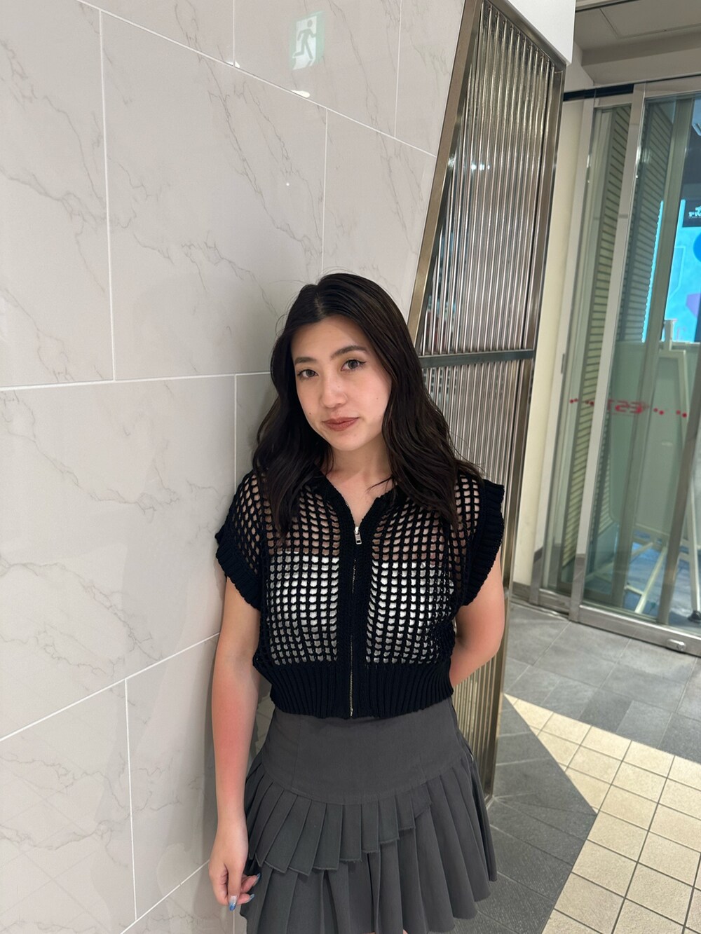 ブラック系のニット/セーター、グレー系のスカート、ブラック系のサンダルを着用したレディースの夏コーディネートの4枚目の写真