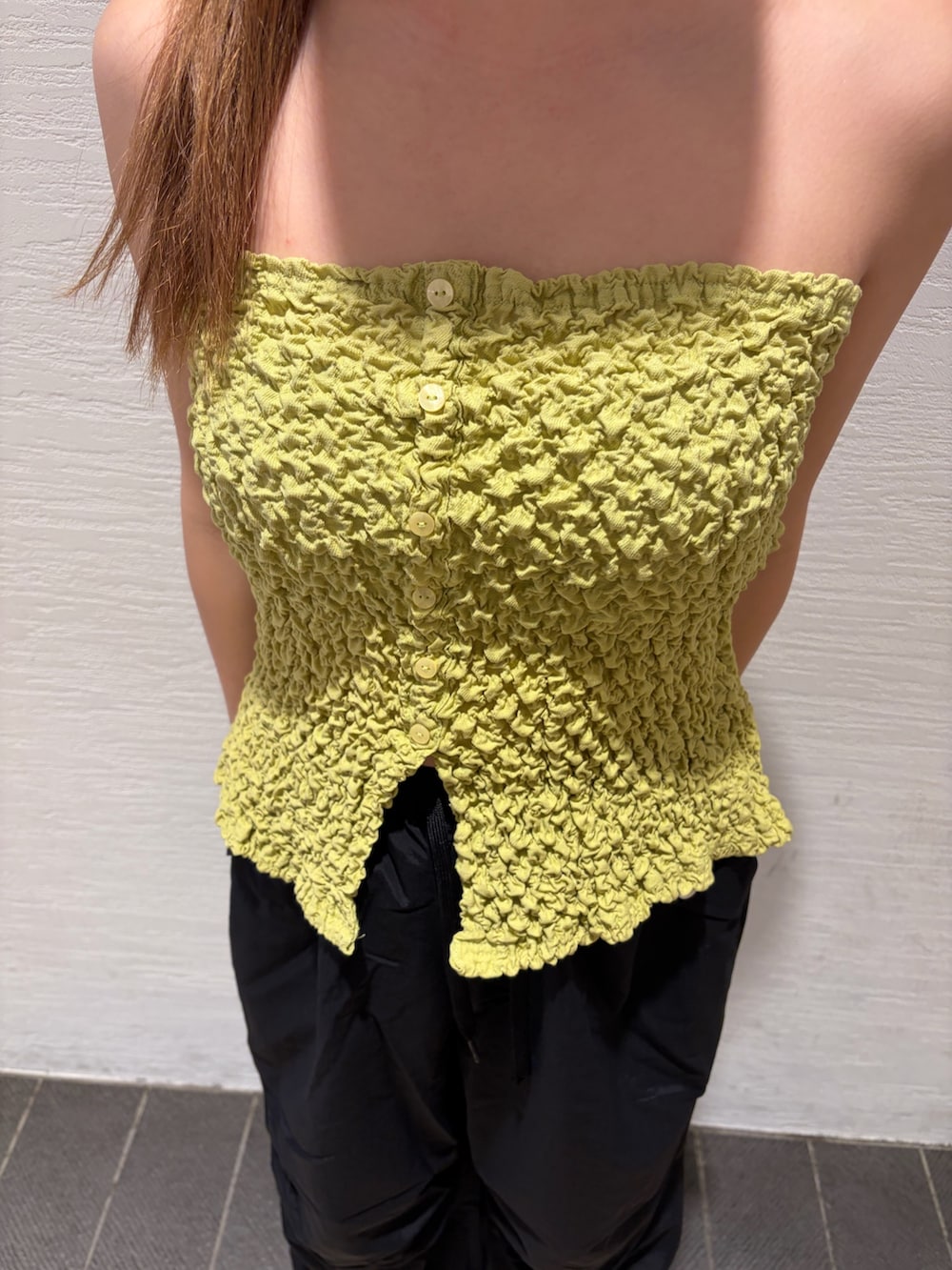 ブラック系のカーゴパンツ、イエロー系のキャミソール、ブルー系のキャップを着用したレディースの春コーディネートの6枚目の写真