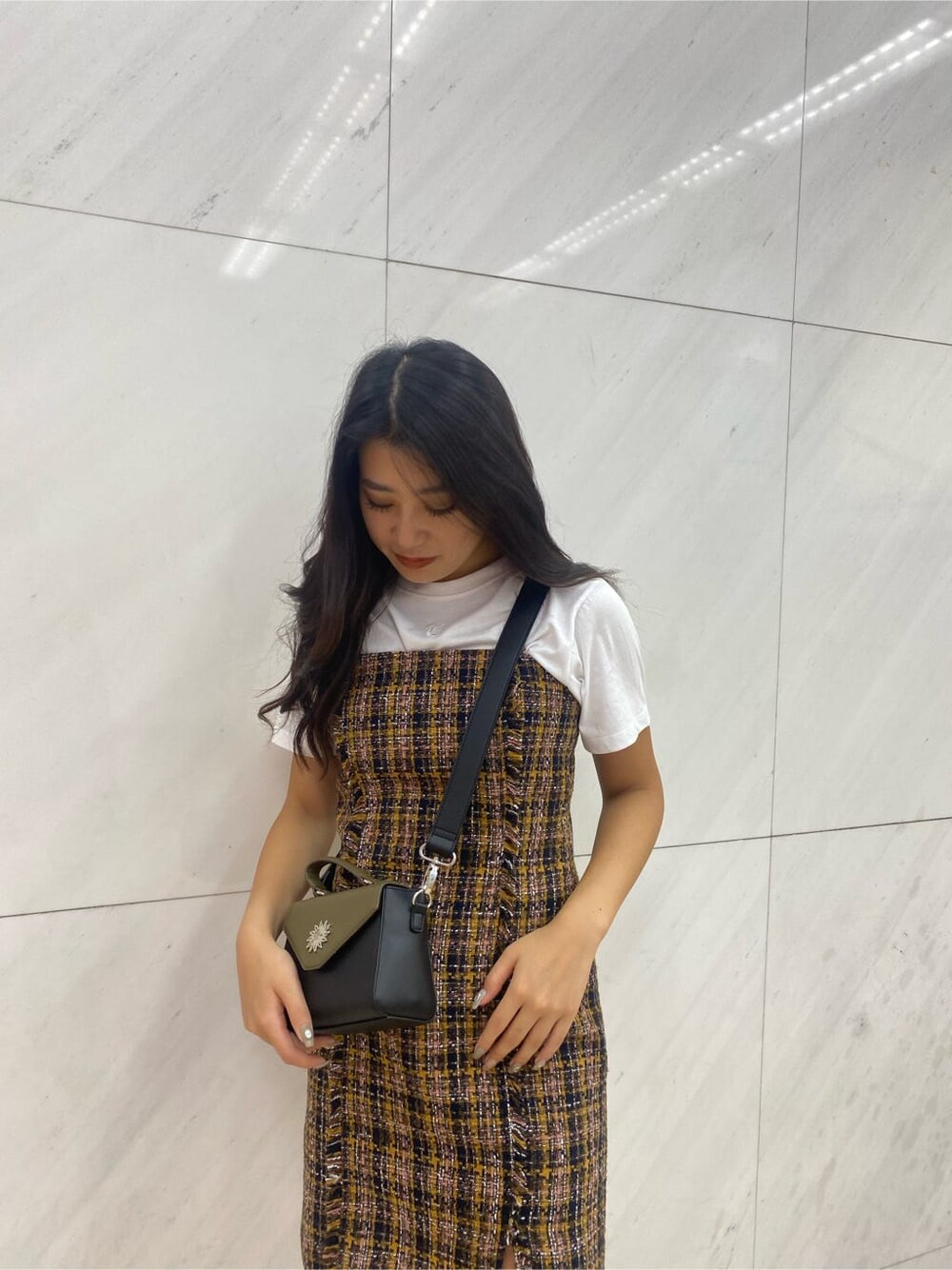 ホワイト系のブーツ、イエロー系のジャンパースカート、ブラック系のショルダーバッグを着用したレディースの夏コーディネートの4枚目の写真