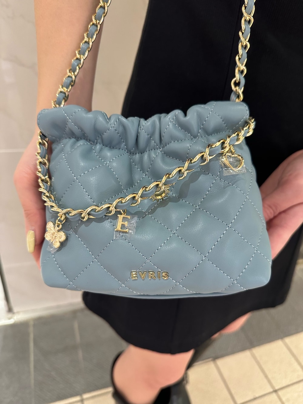 ブルー系のショルダーバッグ、ブラウン系のブーツ、ブラック系のワンピースを着用したレディースの春コーディネートの7枚目の写真