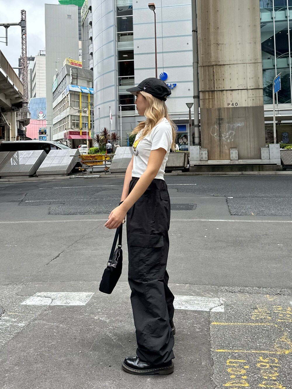 ブラック系のカーゴパンツ、ホワイト系のTシャツ/カットソー、ブラック系のハンドバッグを着用したレディースの夏コーディネートの2枚目の写真