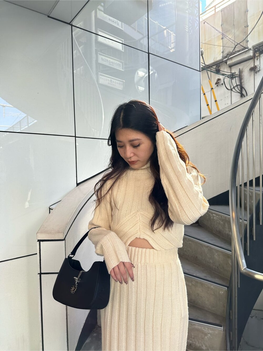 ホワイト系のスカート、ホワイト系のニット/セーター、ブラック系のハンドバッグを着用したレディースの秋コーディネートの3枚目の写真