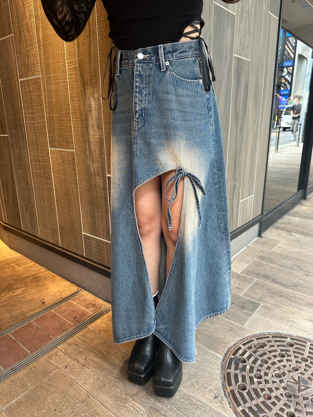 ブルー系のデニムスカート、ブラック系のTシャツ/カットソー、ブラック系のブーツを着用したレディースの秋コーディネートの6枚目の写真