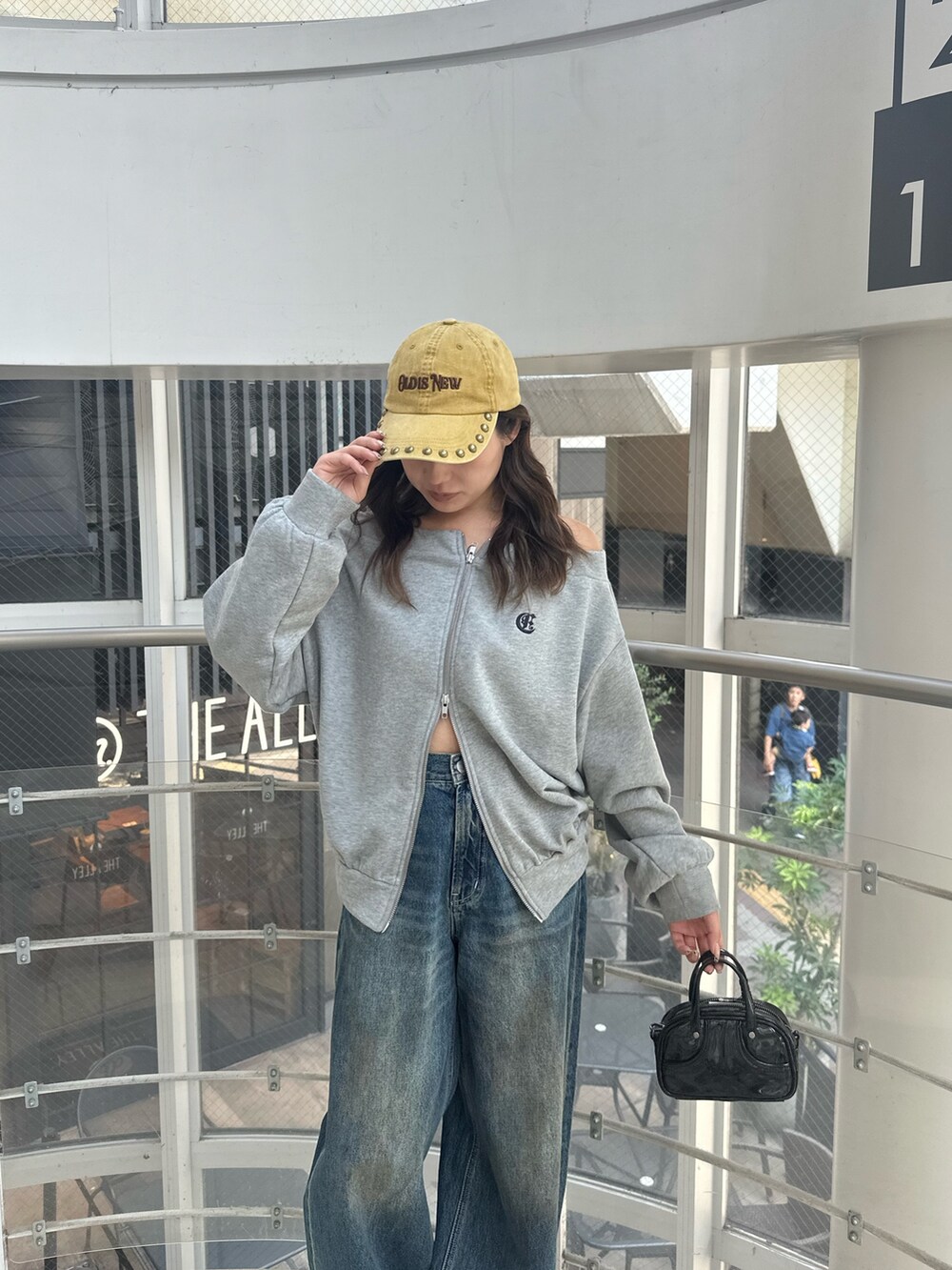 ブルー系のデニムパンツ、グレー系のパーカー、ブラック系のハンドバッグを着用したレディースの秋コーディネートの6枚目の写真