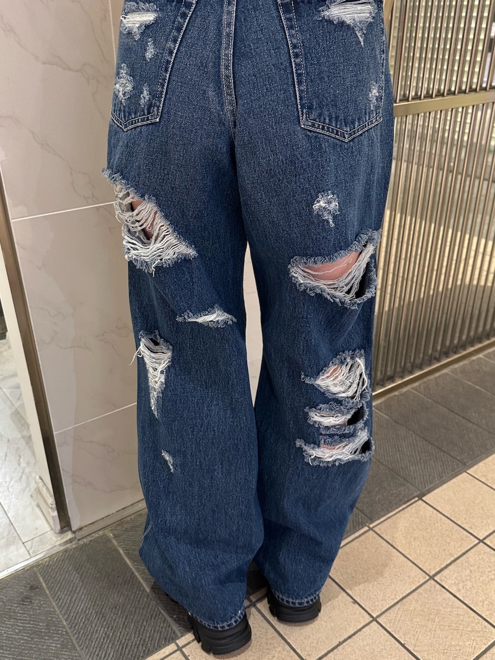 ブルー系のデニムパンツ、ブラック系のサンダル、レッド系のTシャツ/カットソーを着用したレディースの春コーディネートの6枚目の写真