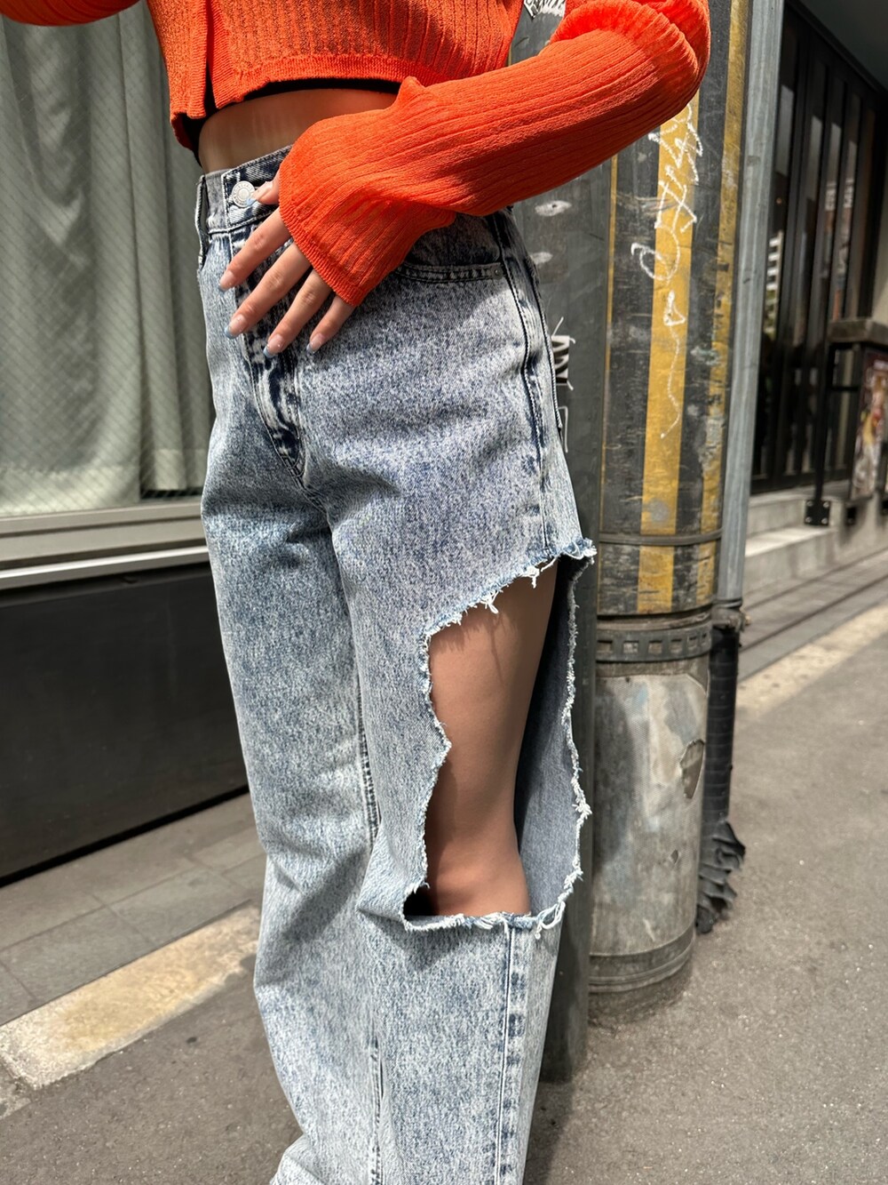 ブルー系のデニムパンツ、ブラック系のサンダル、オレンジ系のカーディガン/ボレロを着用したレディースの春コーディネートの6枚目の写真