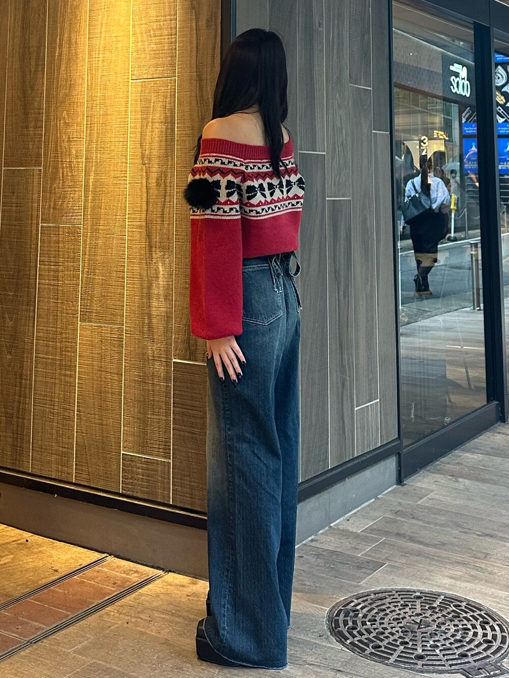 ブルー系のデニムパンツ、レッド系のニット/セーター、ブラック系のブーツを着用したレディースの秋コーディネートの3枚目の写真