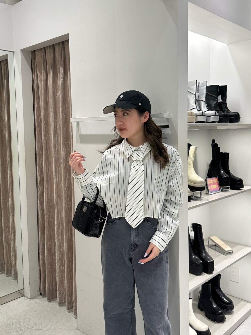 グレー系のデニムパンツ、ホワイト系のシャツ/ブラウス、ブラック系のショルダーバッグを着用したレディースの冬コーディネートの4枚目の写真