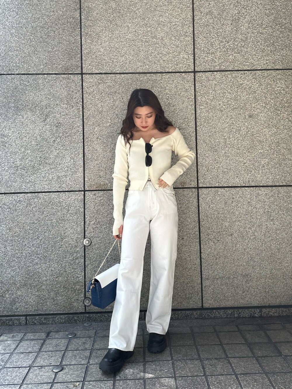 ホワイト系のニット/セーター、ホワイト系のデニムパンツ、ブルー系のショルダーバッグを着用したレディースの春コーディネートの2枚目の写真