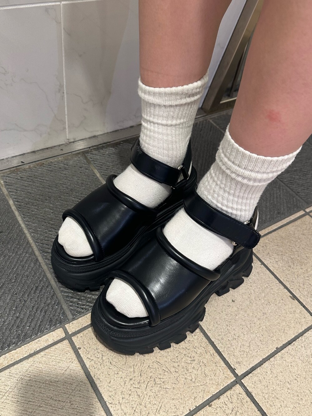 ブラック系のニット/セーター、グレー系のスカート、ブラック系のサンダルを着用したレディースの夏コーディネートの7枚目の写真