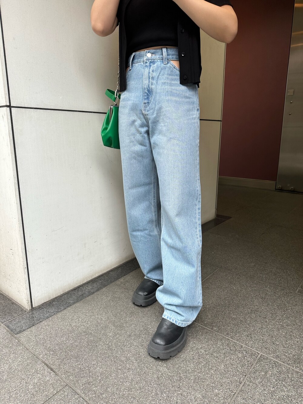 ブラック系のニット/セーター、ブルー系のデニムパンツ、グリーン系のショルダーバッグを着用したレディースの春コーディネートの5枚目の写真