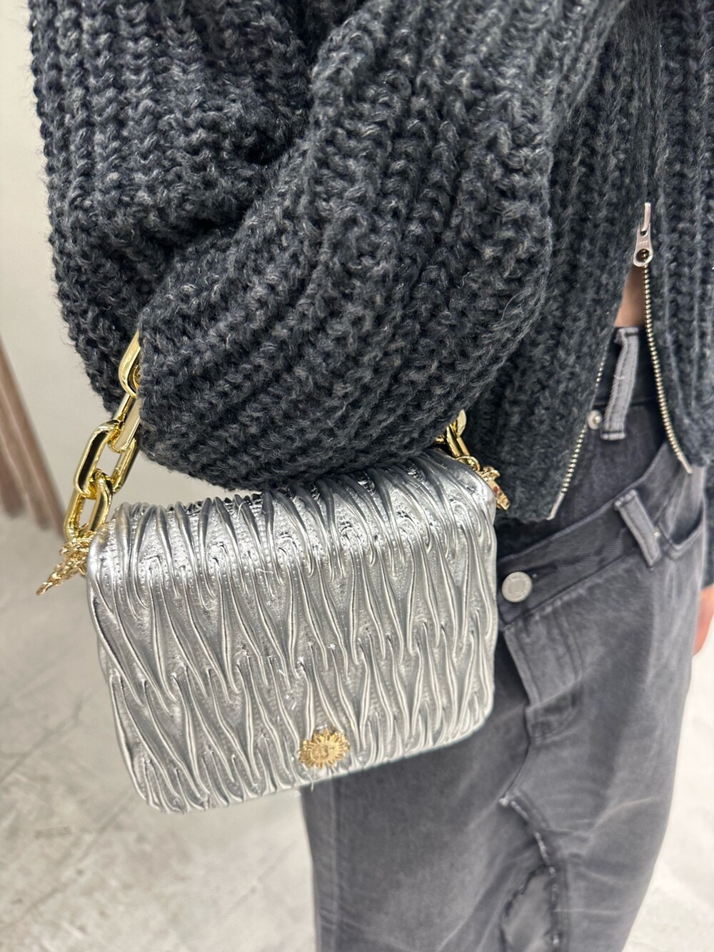 ブラック系のデニムスカート、ブラック系のニット/セーター、ブラック系のブーツを着用したレディースの冬コーディネートの5枚目の写真