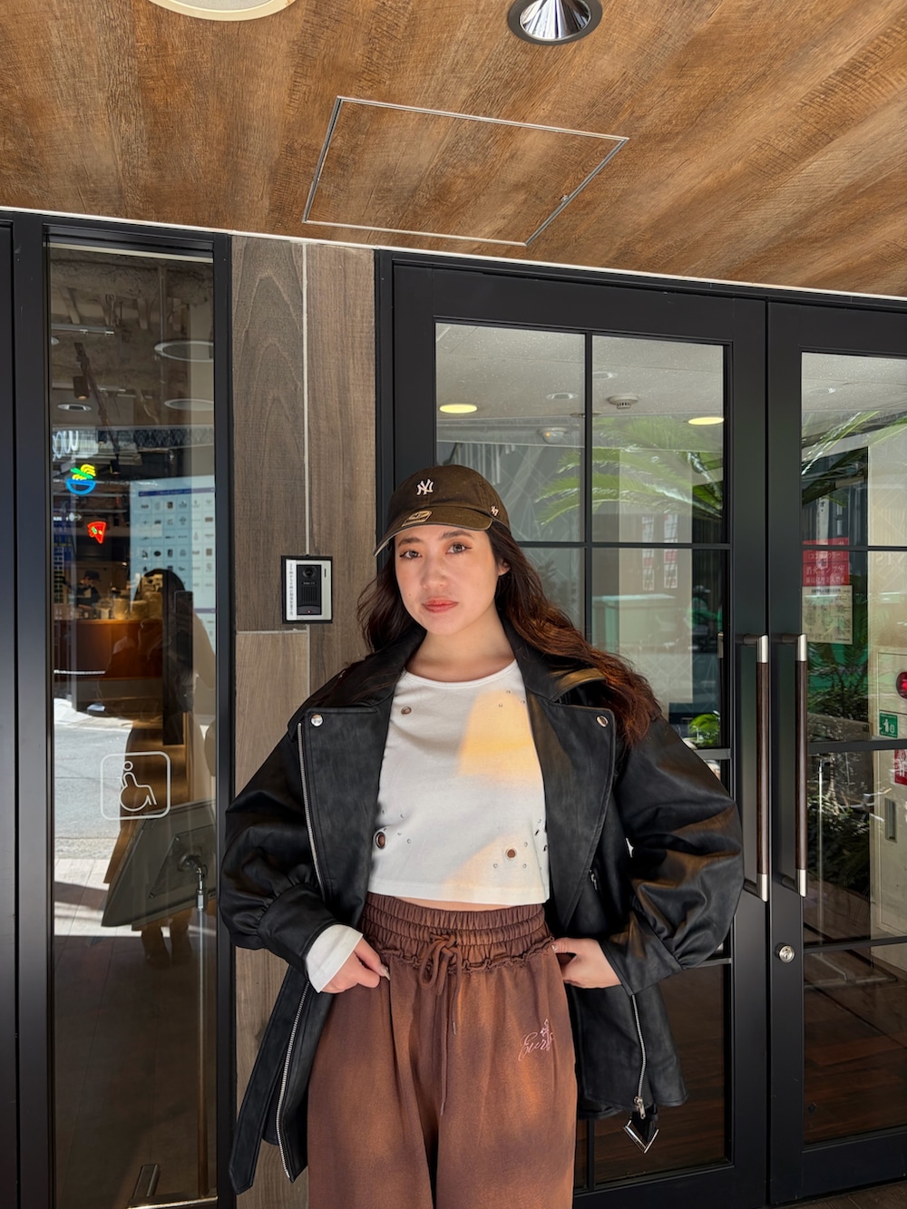 ブラウン系のスウェットパンツ、ブラック系のライダースジャケット、ホワイト系のTシャツ/カットソーを着用したレディースの春コーディネートの5枚目の写真