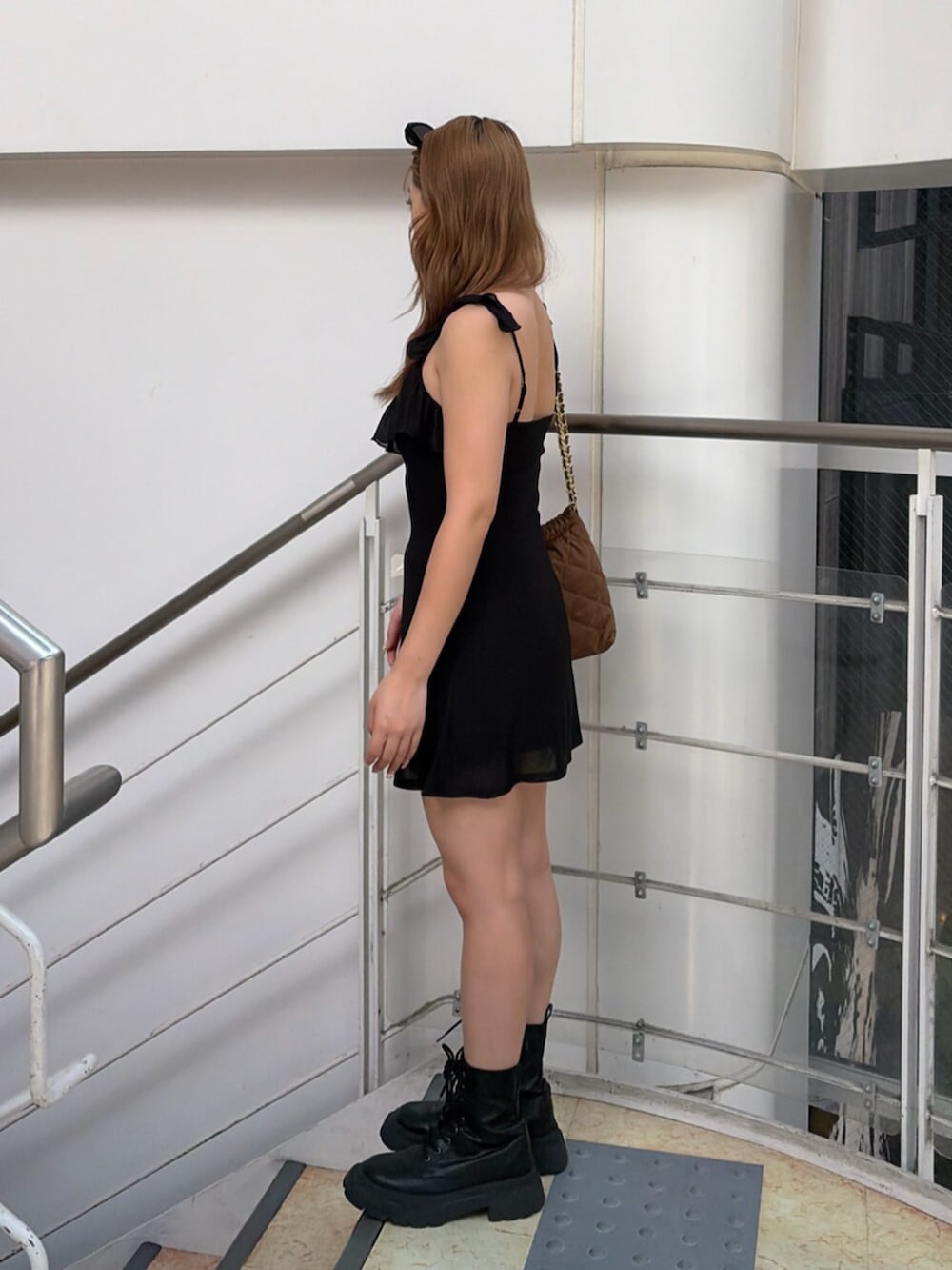 ブラック系のブーツ、ブラック系のワンピース、ブラウン系のショルダーバッグを着用したレディースの夏コーディネートの3枚目の写真