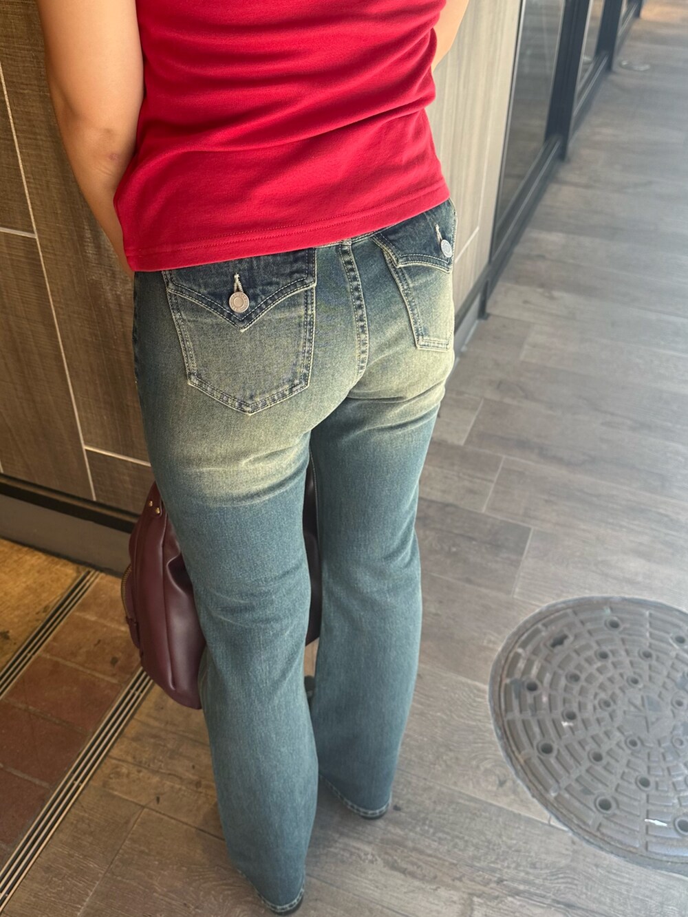 ブルー系のデニムパンツ、レッド系のハンドバッグ、ブラック系のブーツを着用したレディースの秋コーディネートの6枚目の写真