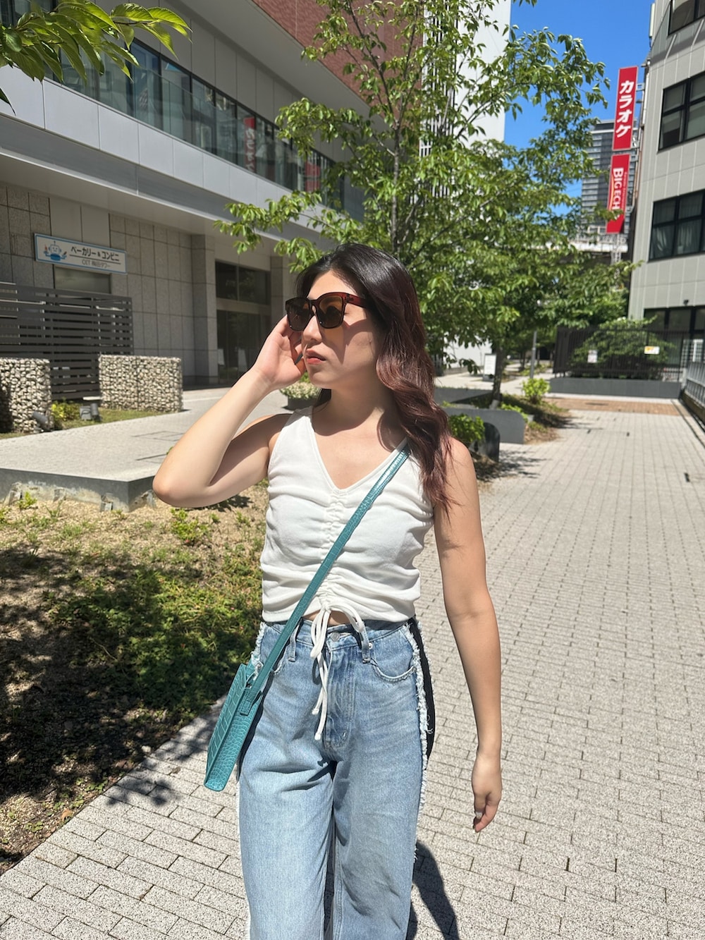 ホワイト系のタンクトップ、ホワイト系のサンダル、ブルー系のデニムパンツを着用したレディースの夏コーディネートの5枚目の写真