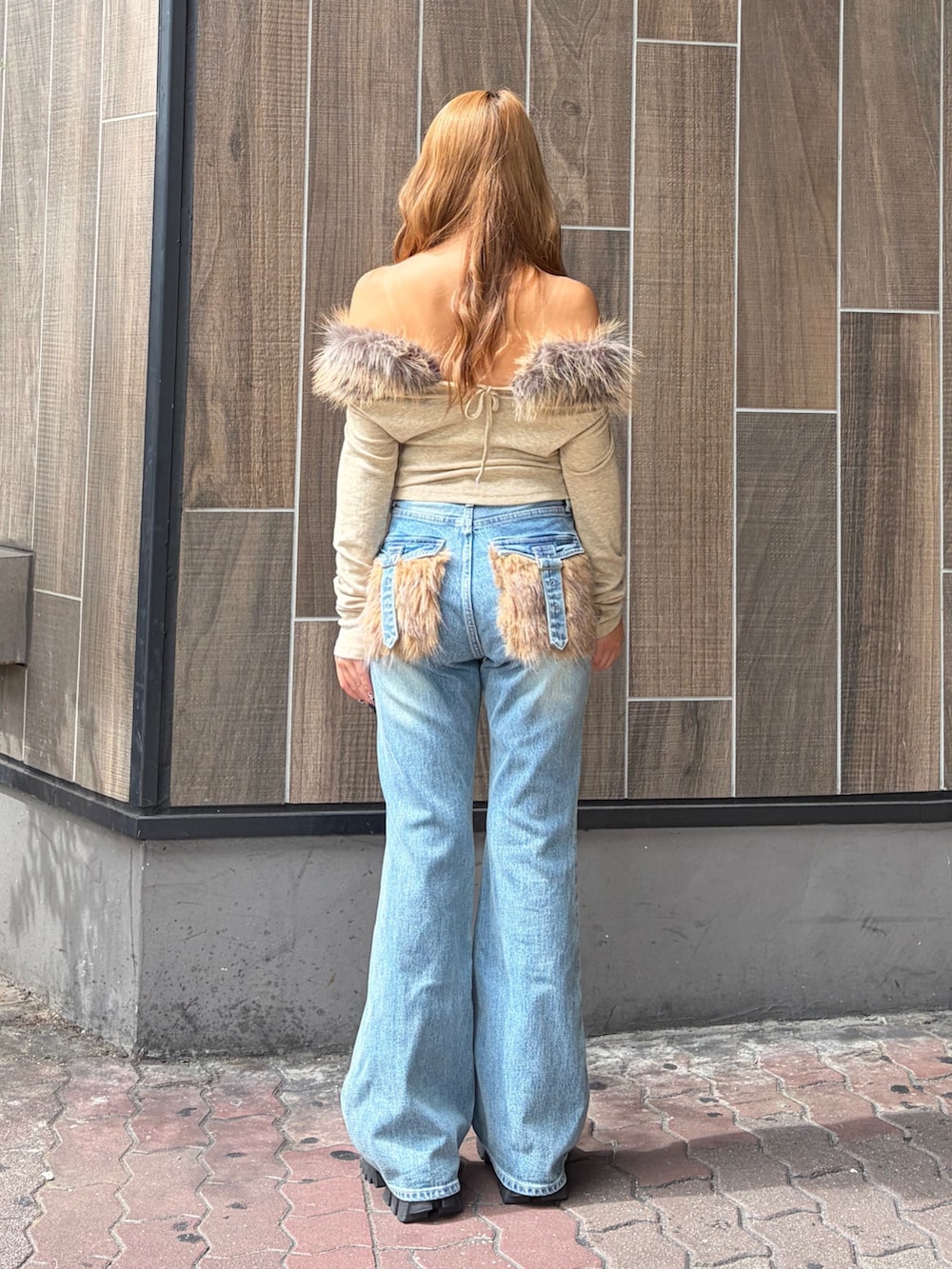 ブルー系のデニムパンツ、ベージュ系のTシャツ/カットソー、ブラック系のブーツを着用したレディースの秋コーディネートの3枚目の写真