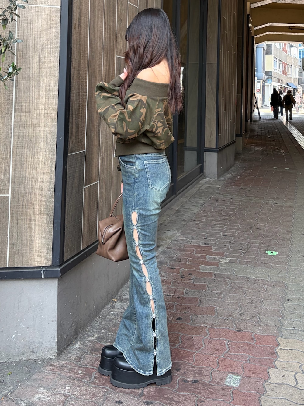 ブルー系のデニムパンツ、ブラウン系のボストンバッグ、ブラック系のブーツを着用したレディースの冬コーディネートの2枚目の写真