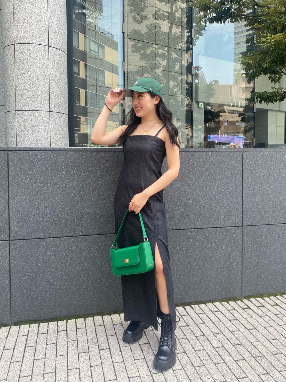 ブラック系のワンピース、グリーン系のショルダーバッグ、ブラック系のブーツを着用したレディースの夏コーディネートの2枚目の写真