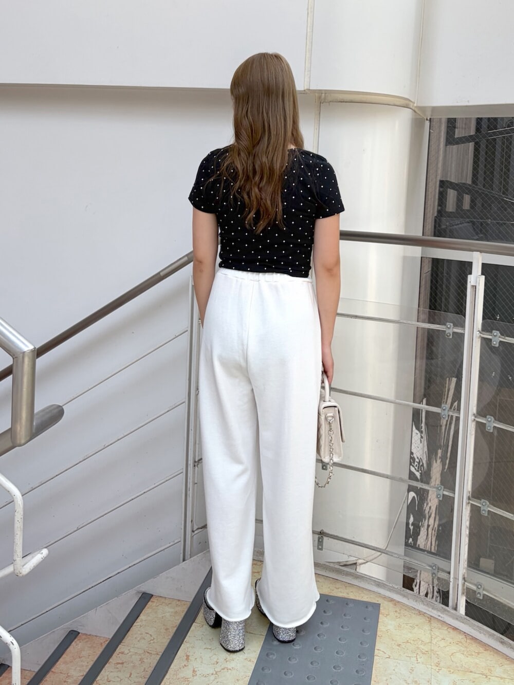 シルバー系のサンダル、ホワイト系のスウェットパンツ、ブラック系のTシャツ/カットソーを着用したレディースの夏コーディネートの3枚目の写真