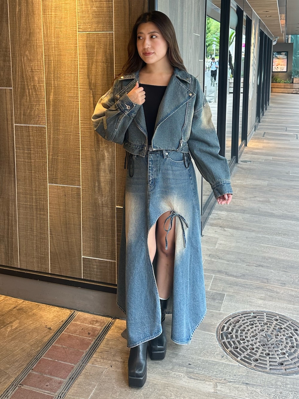 ブルー系のデニムスカート、ブラック系のTシャツ/カットソー、ブラック系のブーツを着用したレディースの秋コーディネートの5枚目の写真