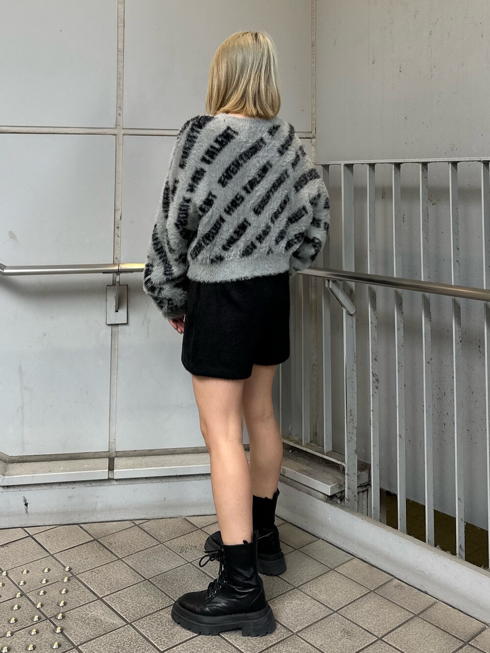 ブラック系のその他パンツ、ブラック系のブーツ、グレー系のニット/セーターを着用したレディースの冬コーディネートの2枚目の写真