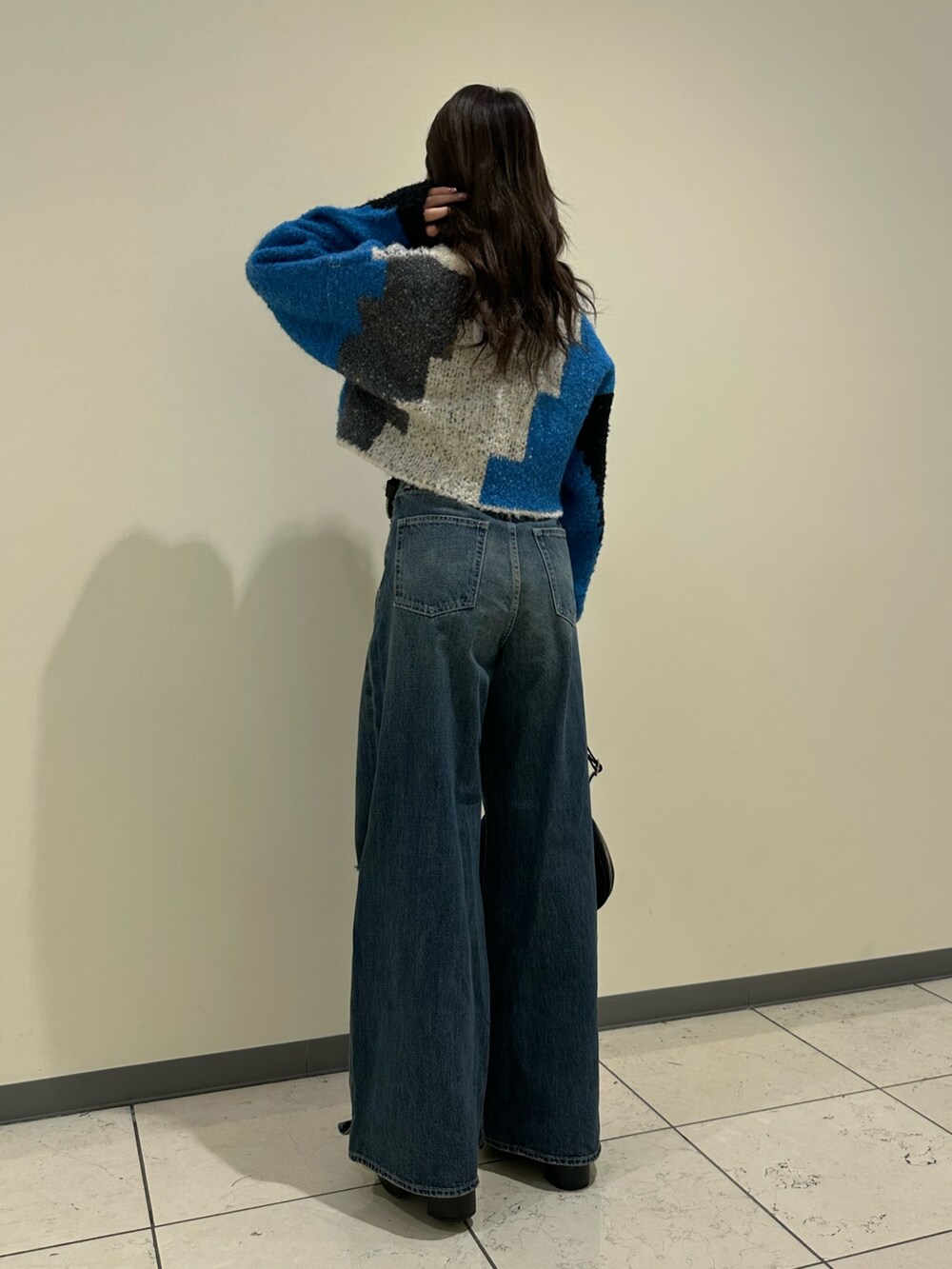 ブルー系のデニムパンツ、ブラック系のショルダーバッグ、ブラック系のブーツを着用したレディースの冬コーディネートの3枚目の写真