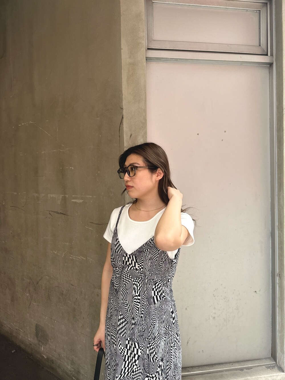 ブラック系のワンピース、ホワイト系のTシャツ/カットソー、ブラック系のハンドバッグを着用したレディースの春コーディネートの4枚目の写真