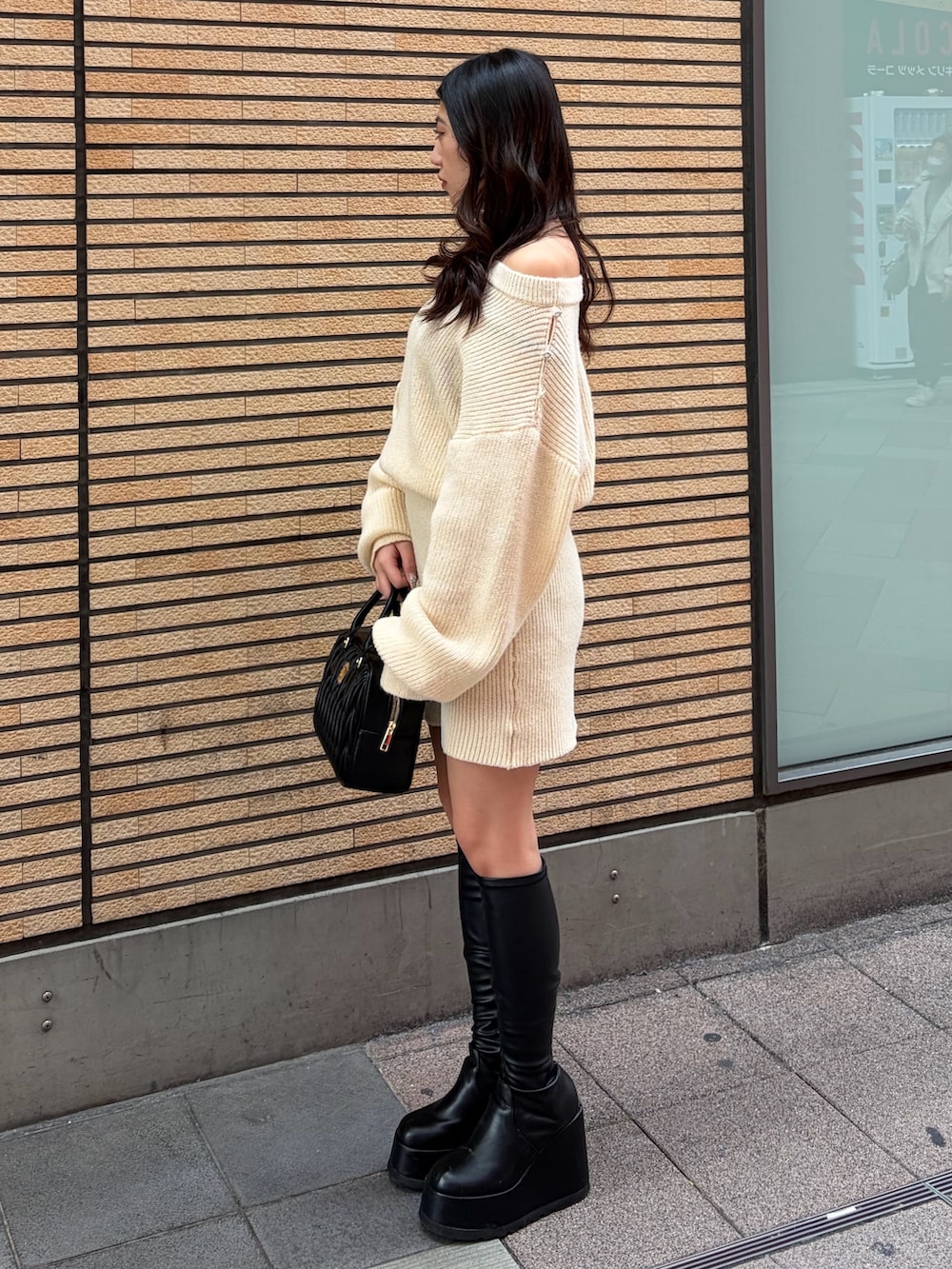 ブラック系のブーツ、ホワイト系のワンピース、ブラック系のハンドバッグを着用したレディースの冬コーディネートの3枚目の写真