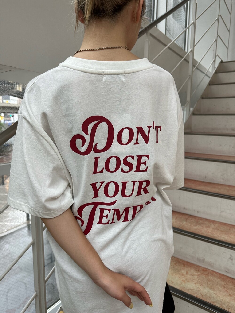 ホワイト系のTシャツ/カットソー、ブラック系のブーツ、ブラック系のハンドバッグを着用したレディースの夏コーディネートの6枚目の写真