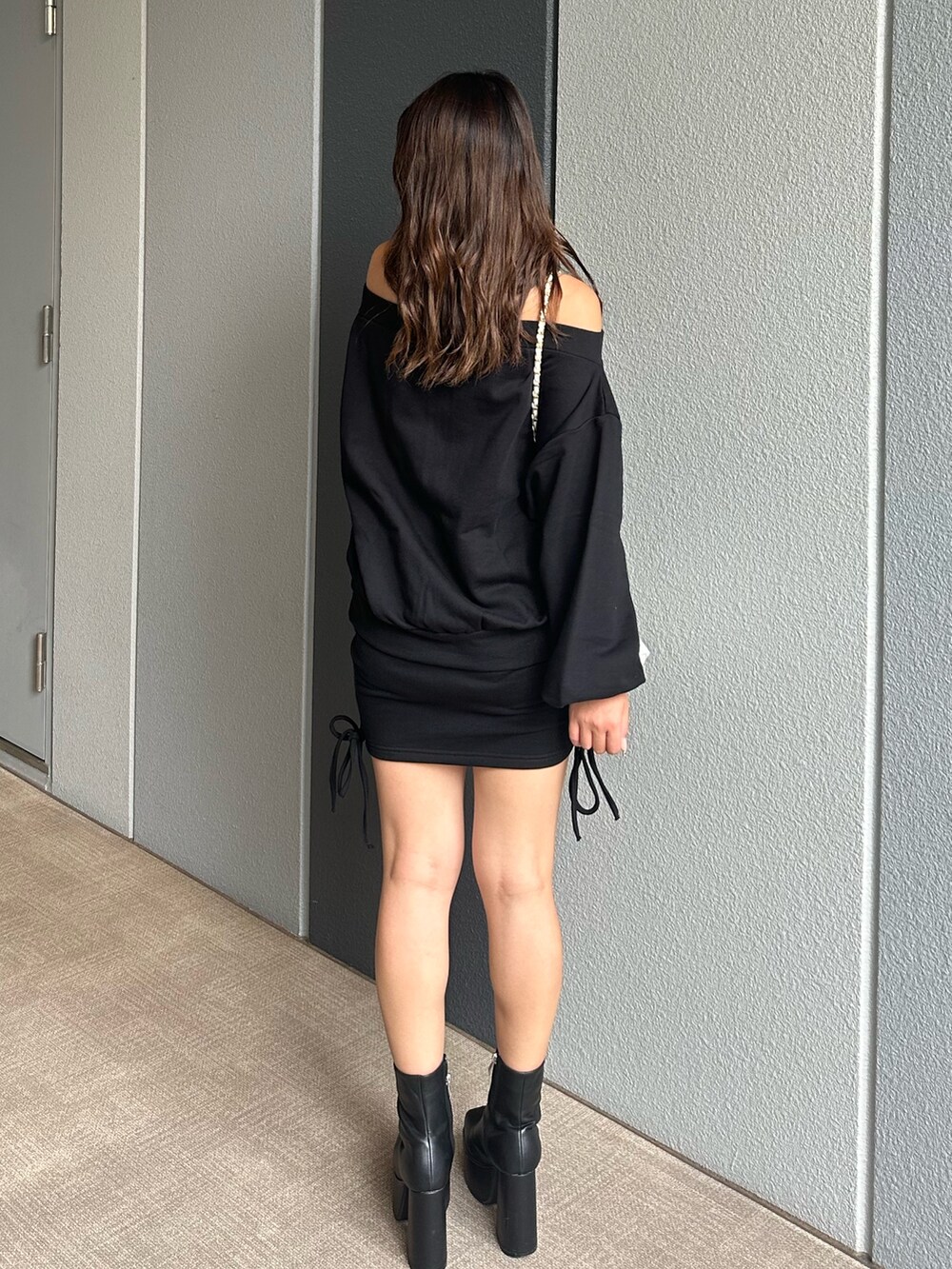 ブラック系のパーカー、ブラック系のスカート、ブラック系のブーツを着用したレディースの秋コーディネートの3枚目の写真