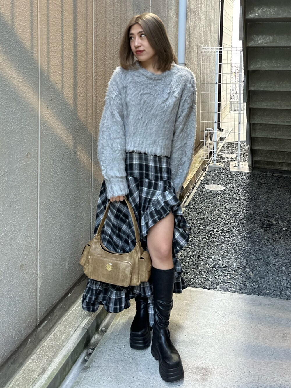 グレー系のニット/セーター、ブラック系のスカート、ブラック系のブーツを着用したレディースの冬コーディネートの2枚目の写真