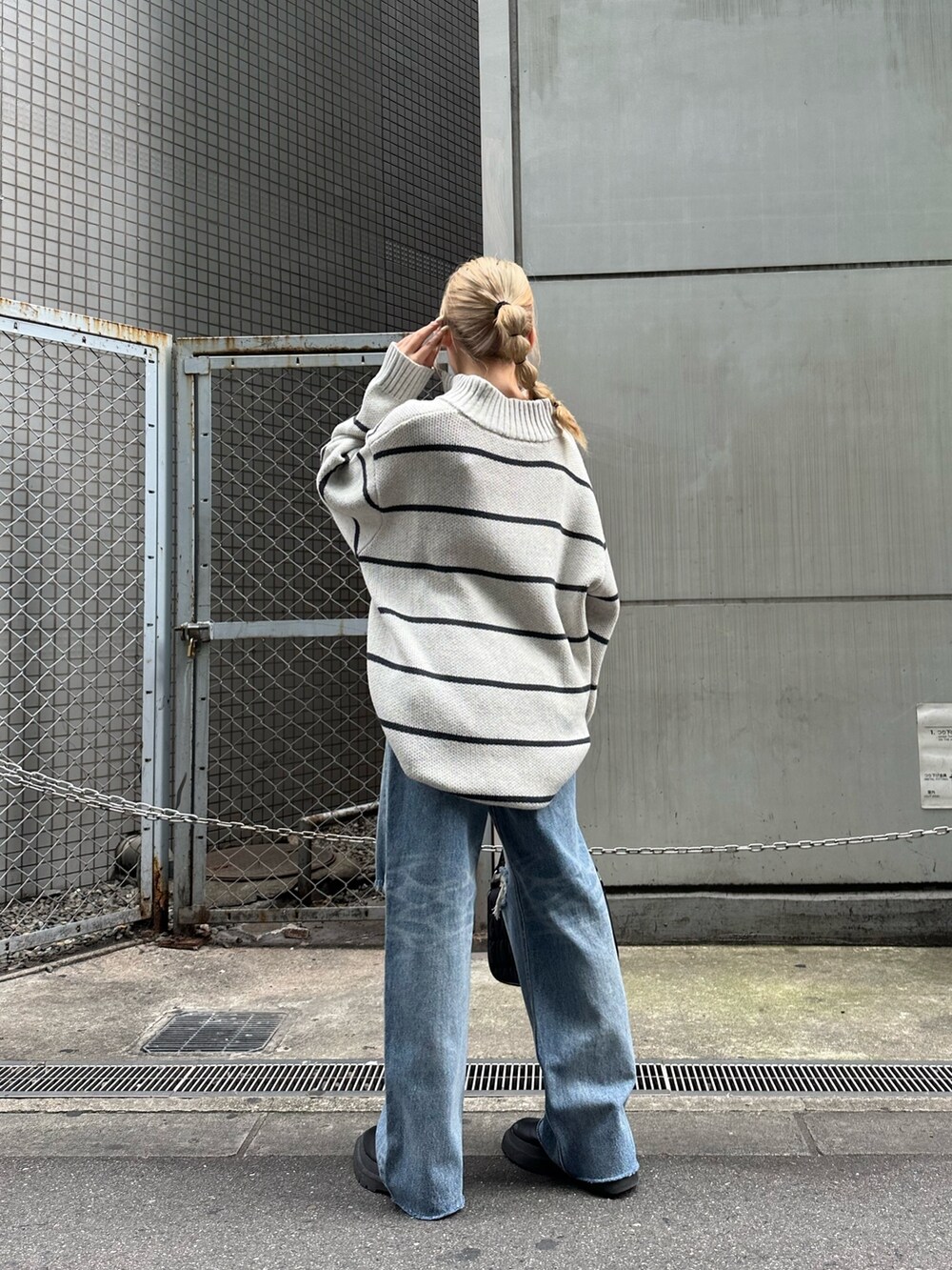 ブラック系のデニムパンツ、ブラック系のハンドバッグ、その他のニット/セーターを着用したレディースの夏コーディネートの3枚目の写真