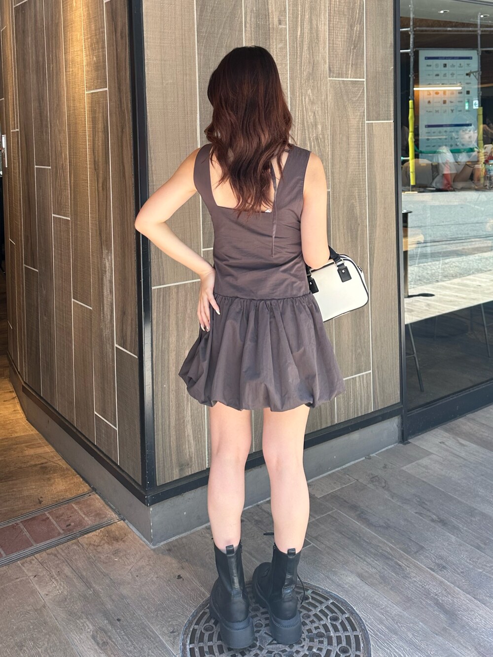 グレー系のワンピース、ホワイト系のショルダーバッグ、ブラック系のブーツを着用したレディースの夏コーディネートの4枚目の写真